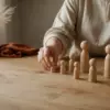 женские руки расставляют деревянные фигурки-заместители на столе, настольная семейная расстановка