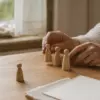 Женские руки расставляют деревянные фигурки-заместители на столе во время расстановки на деньги