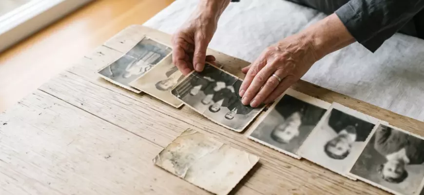 Родовые сценарии в отношениях: женские руки раскладывают старые семейные фотографии трёх поколений